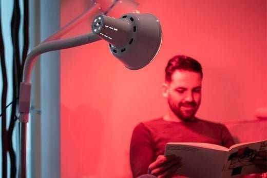 Man leest een boek onder een infraroodlamp op statief, de woonkamer in rood licht